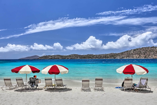 A beach with three sun umbrellas and four lounge chairs. - Saint Thomas Condo w/ Ocean Views, Walk to Beach! (St. Thomas)