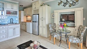 A kitchen with white cabinets, a refrigerator, and a dining area with patterned chairs and a table. - Saint Thomas Condo w/ Ocean Views, Walk to Beach! (St. Thomas)