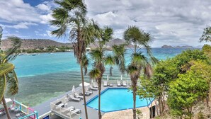A pool area with lounge chairs and a view of the ocean. - Saint Thomas Condo w/ Ocean Views, Walk to Beach! (St. Thomas)