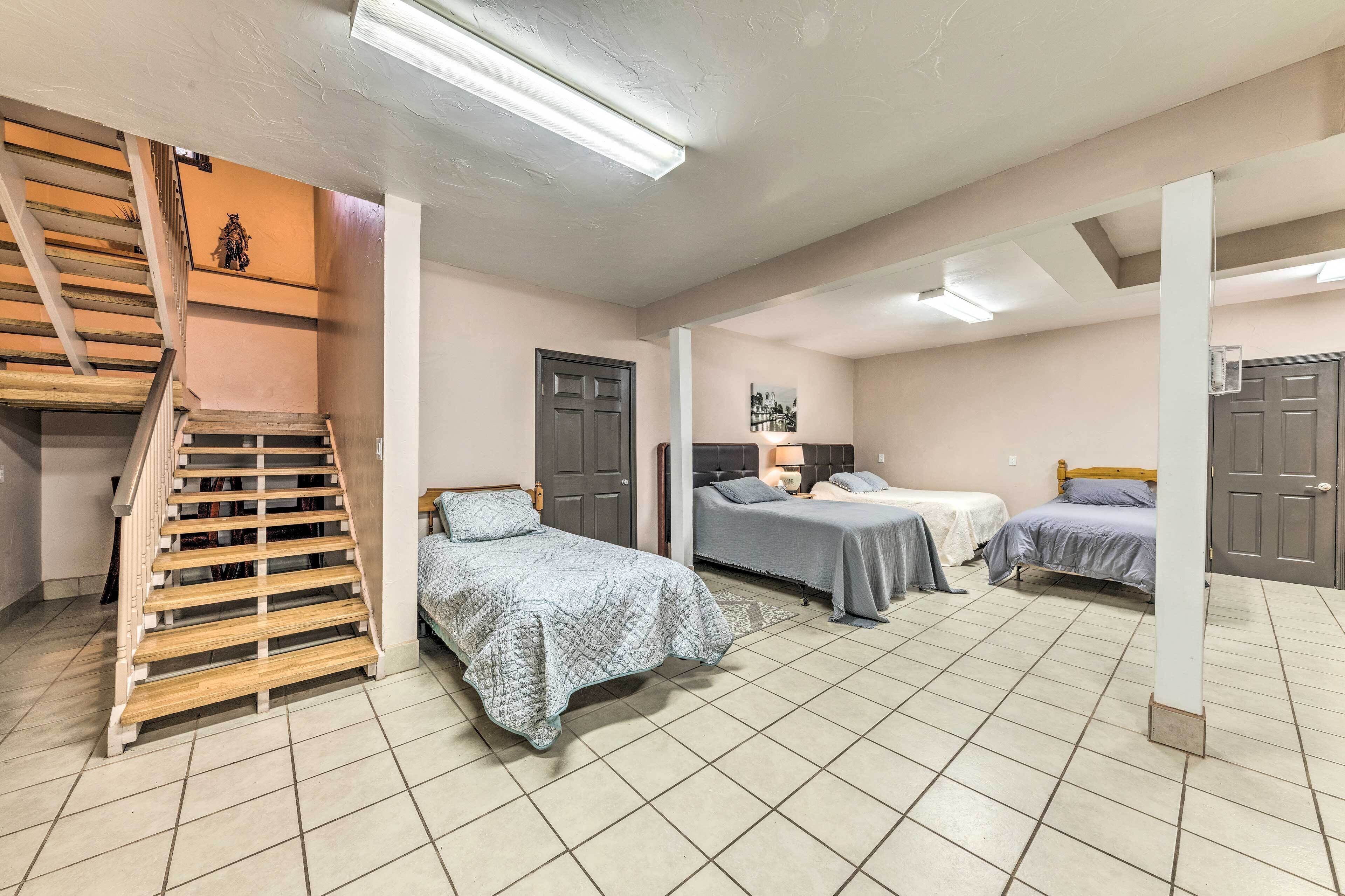 A room with three beds, a staircase, and a door.