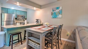 A compact kitchen with a central island, stainless steel appliances, and a dining area with a table and chairs. - Reeds Spring Condo Near Aquarium at the Boardwalk! (Branson West)