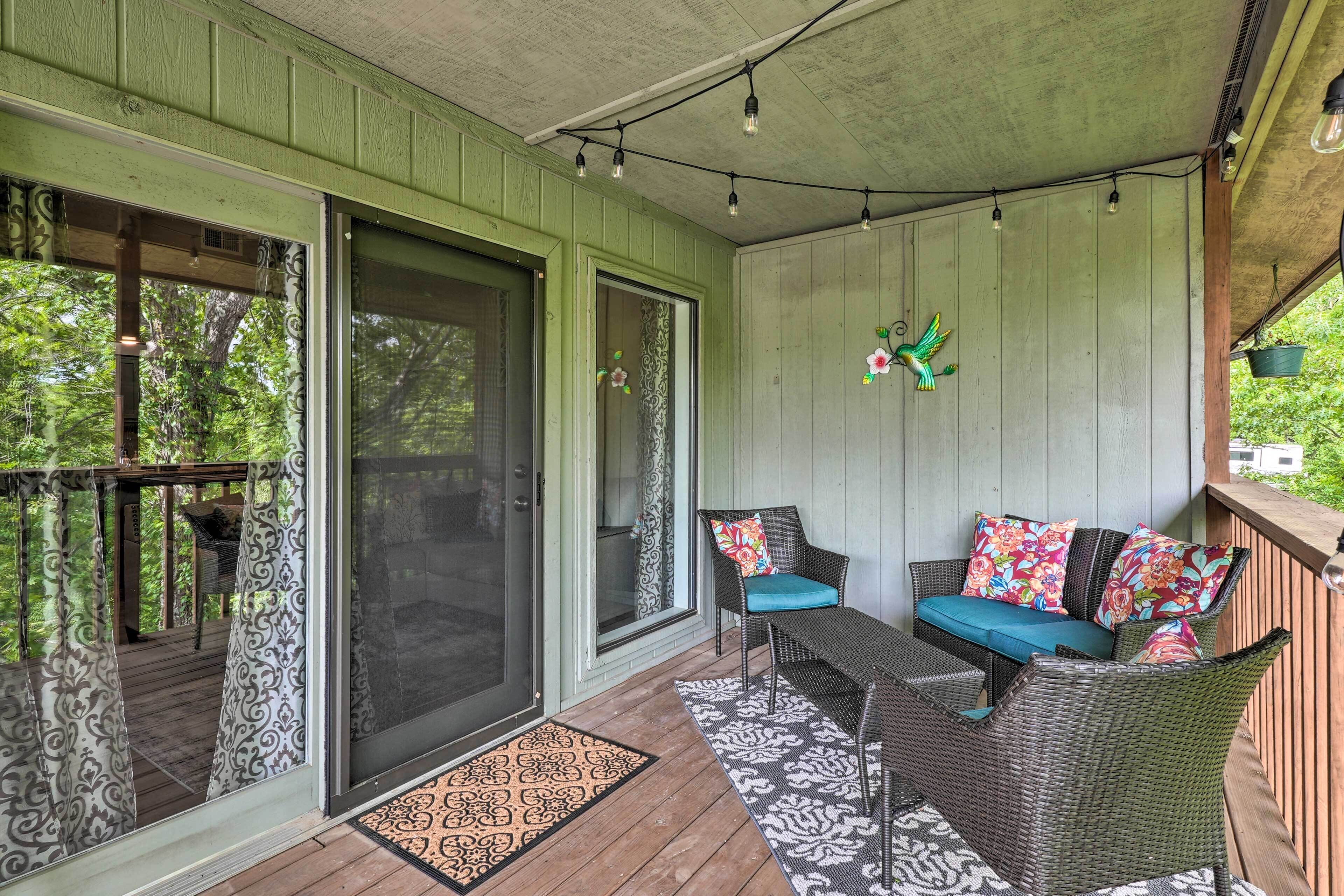 A covered porch with wicker furniture, a sliding glass door, and string lights.