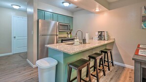 A modern kitchen with stainless steel appliances, a granite countertop, and bar stools. - Reeds Spring Condo Near Aquarium at the Boardwalk! (Branson West)