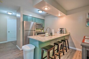 A modern kitchen with stainless steel appliances, a granite countertop, and bar stools.