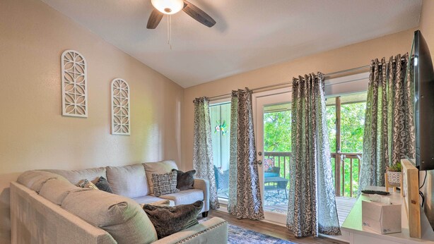 A living room with a sofa, a ceiling fan, and a view through large glass doors to an outdoor deck. - Reeds Spring Condo Near Aquarium at the Boardwalk! (Branson West)