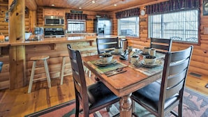 A wooden cabin interior with a kitchen, dining area, and a large window. - Rustic Cabin in Roaring River State Park! (Eagle Rock)