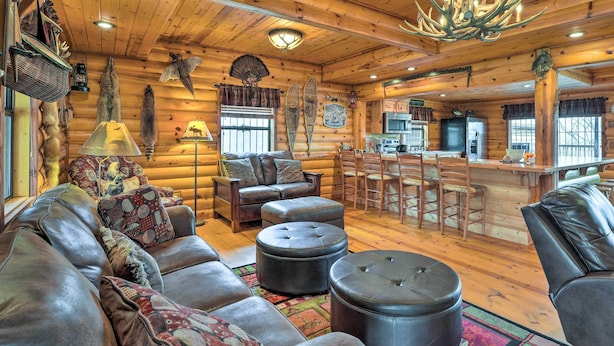 A log cabin interior with a leather sofa, ottomans, a dining area, and a kitchen. - Rustic Cabin in Roaring River State Park! (Eagle Rock)