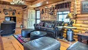 A log cabin interior with a leather sofa, ottomans, a fireplace, and rustic decor. - Rustic Cabin in Roaring River State Park! (Eagle Rock)