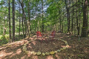 A forest clearing with a table and two chairs surrounded by a circle of stones. - Romantic Asheville Area Cabin w/ Deck & Hot Tub! (Leicester)