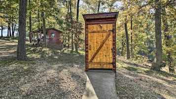 Una cabaña de madera con un gran ventanal y un porche, rodeada de árboles.