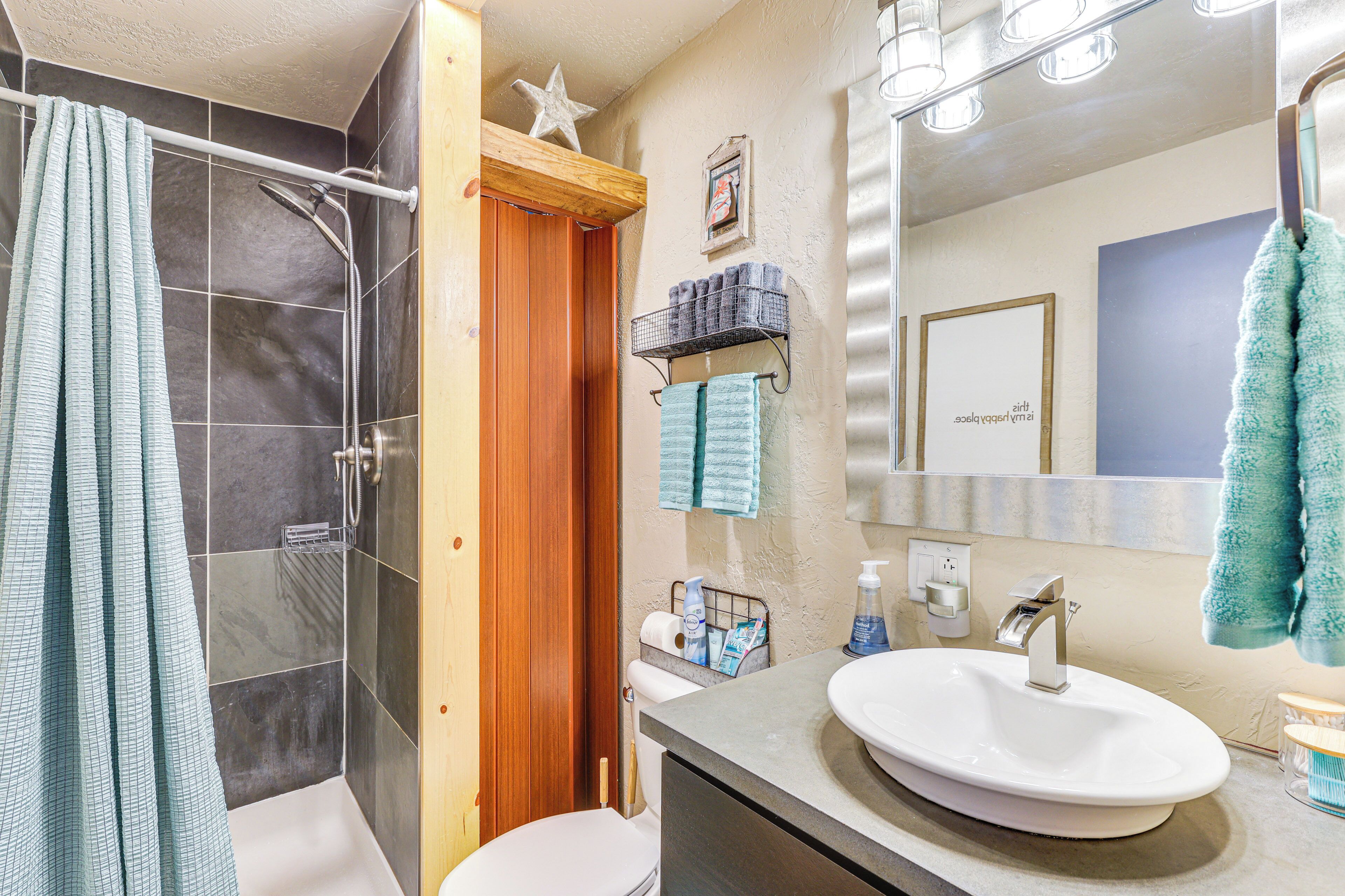 A bathroom with a shower, toilet, sink, and vanity.