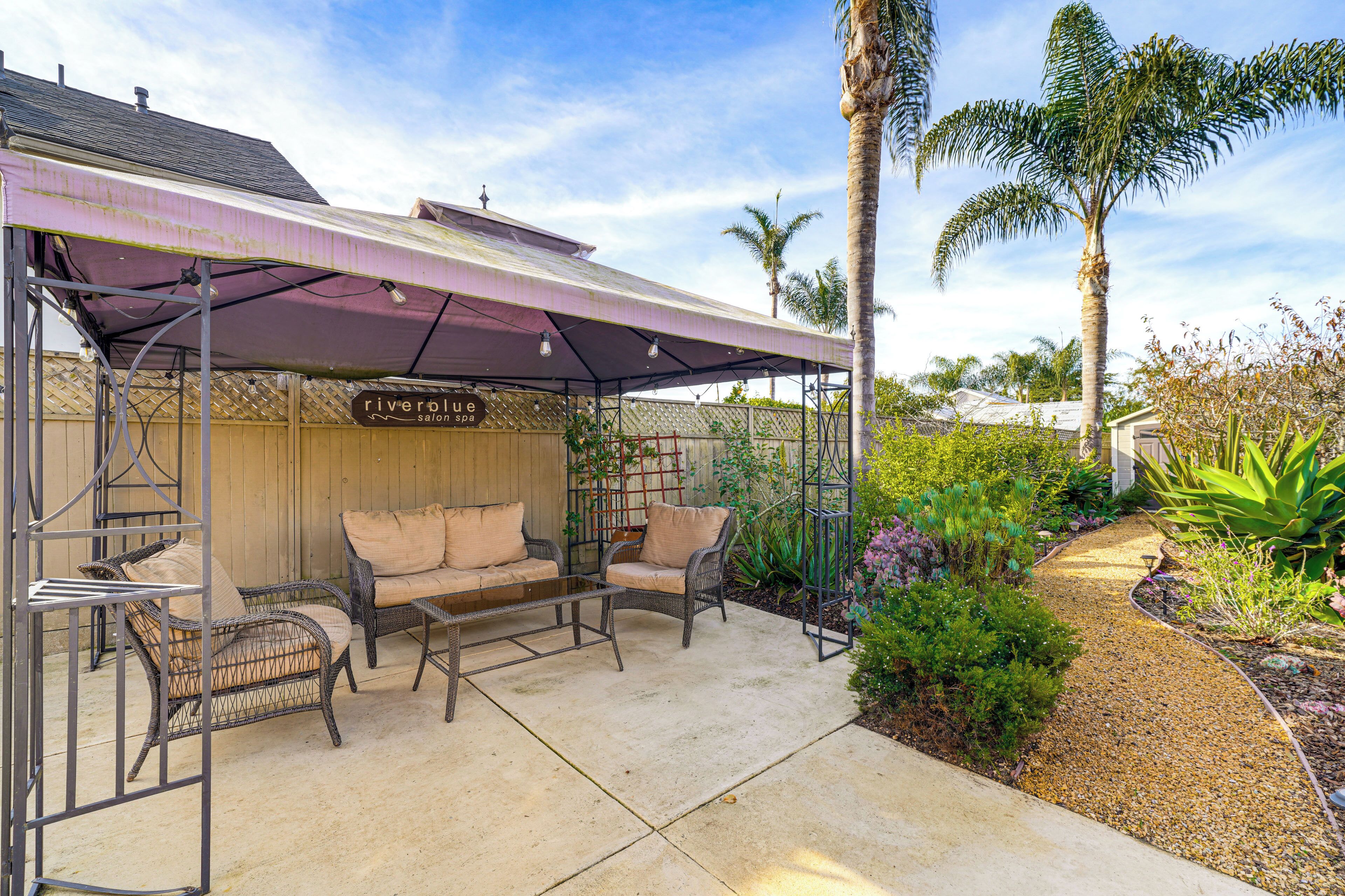 A covered outdoor seating area with wicker furniture and a sign for 'riverplc spa'.
