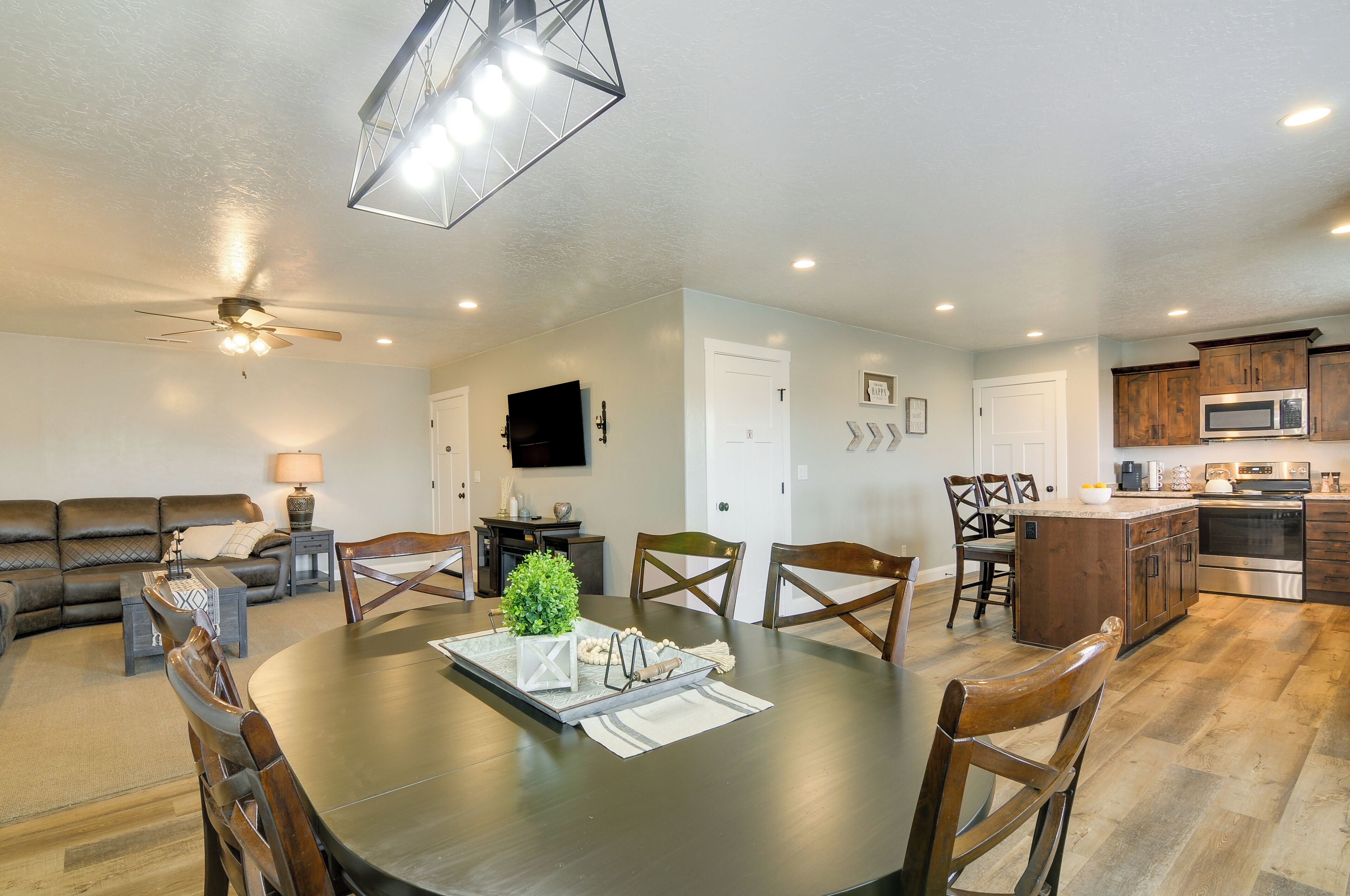 A modern living room with a dark wooden dining table, a sofa, and a ceiling fan.