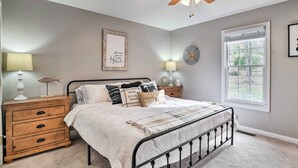 A bedroom with a bed, nightstands, a ceiling fan, a window, and wall decor. - Secluded Retreat on 2 Acres Near Dale Hollow Lake! (Burkesville)
