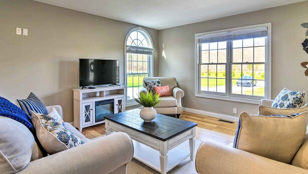 A living room with a TV, two sofas, a coffee table, and a window with a view of a car and greenery outside. - Secluded Retreat on 2 Acres Near Dale Hollow Lake! (Burkesville)