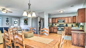 A spacious kitchen with wooden cabinets, a stainless steel refrigerator, and a dining area with a wooden table and chairs. - Secluded Retreat on 2 Acres Near Dale Hollow Lake! (Burkesville)