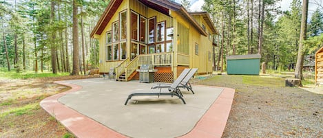 Een lodge met een groot terras, een overdekt picknickgedeelte en uitzicht op het omliggende bos.