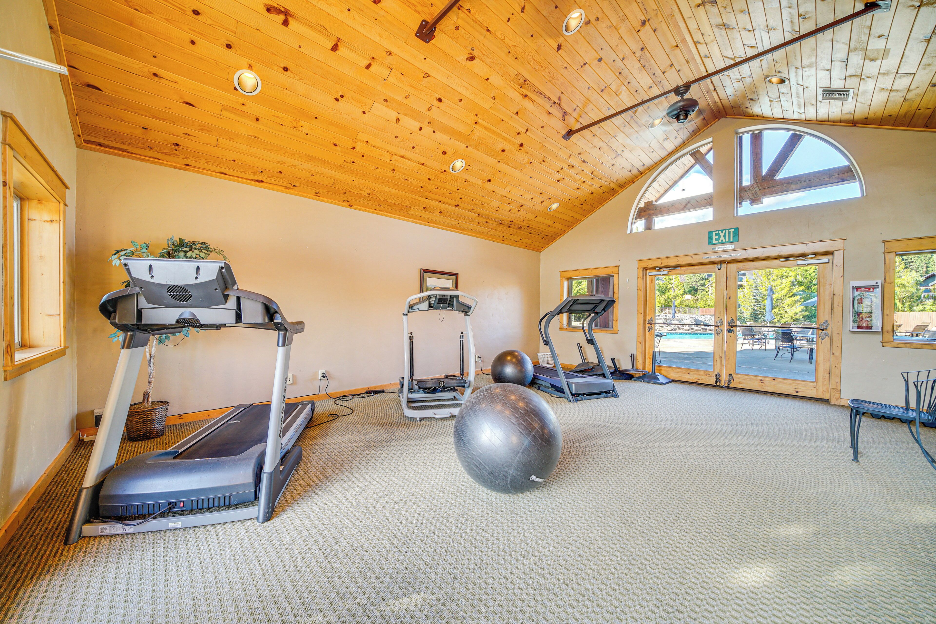 A gym with treadmills, elliptical machines, and exercise balls.