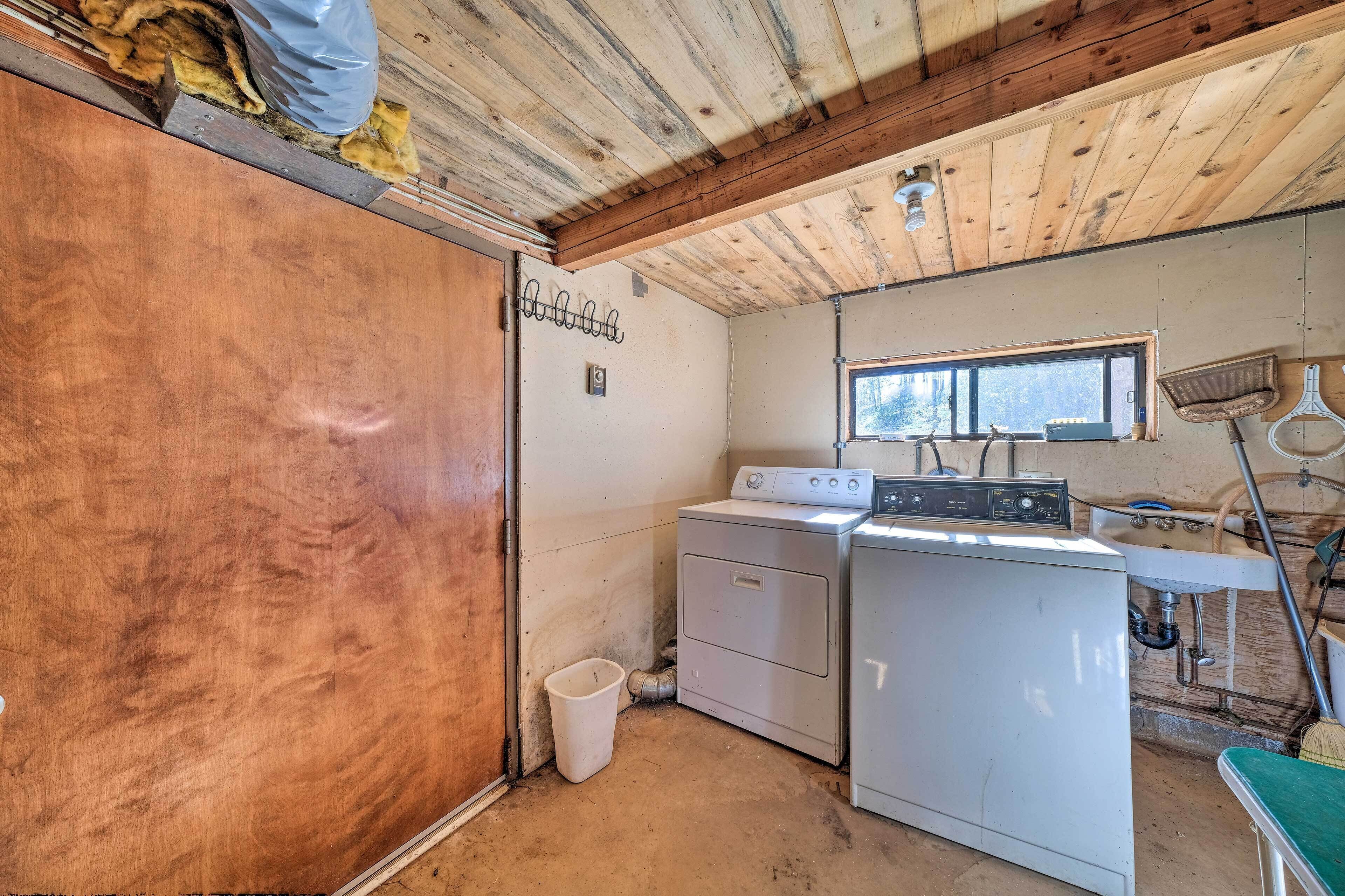 A laundry room with a washing machine, a dryer, a window, and a wooden ceiling.
