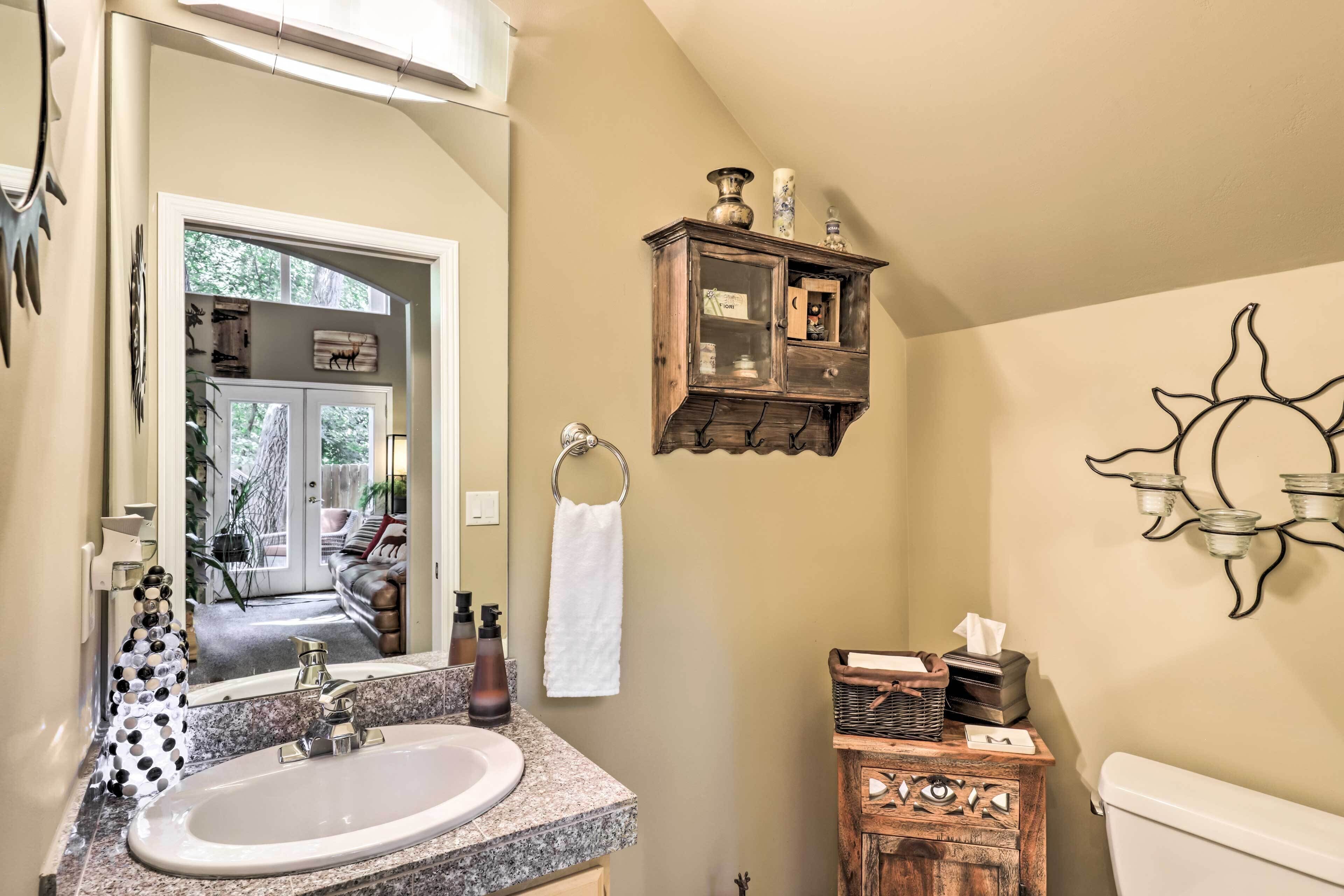 A bathroom with a sink, mirror, towel rack, and a small wooden cabinet with decorative items.