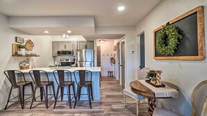 Una cocina moderna con una isla central, taburetes de bar y una mesa de comedor con sillas.