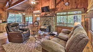 A cozy cabin interior with a stone fireplace, leather recliner, and a stone wall. - Secluded Stanardsville Cabin w/ 10 Acres & Hot Tub (Stanardsville)