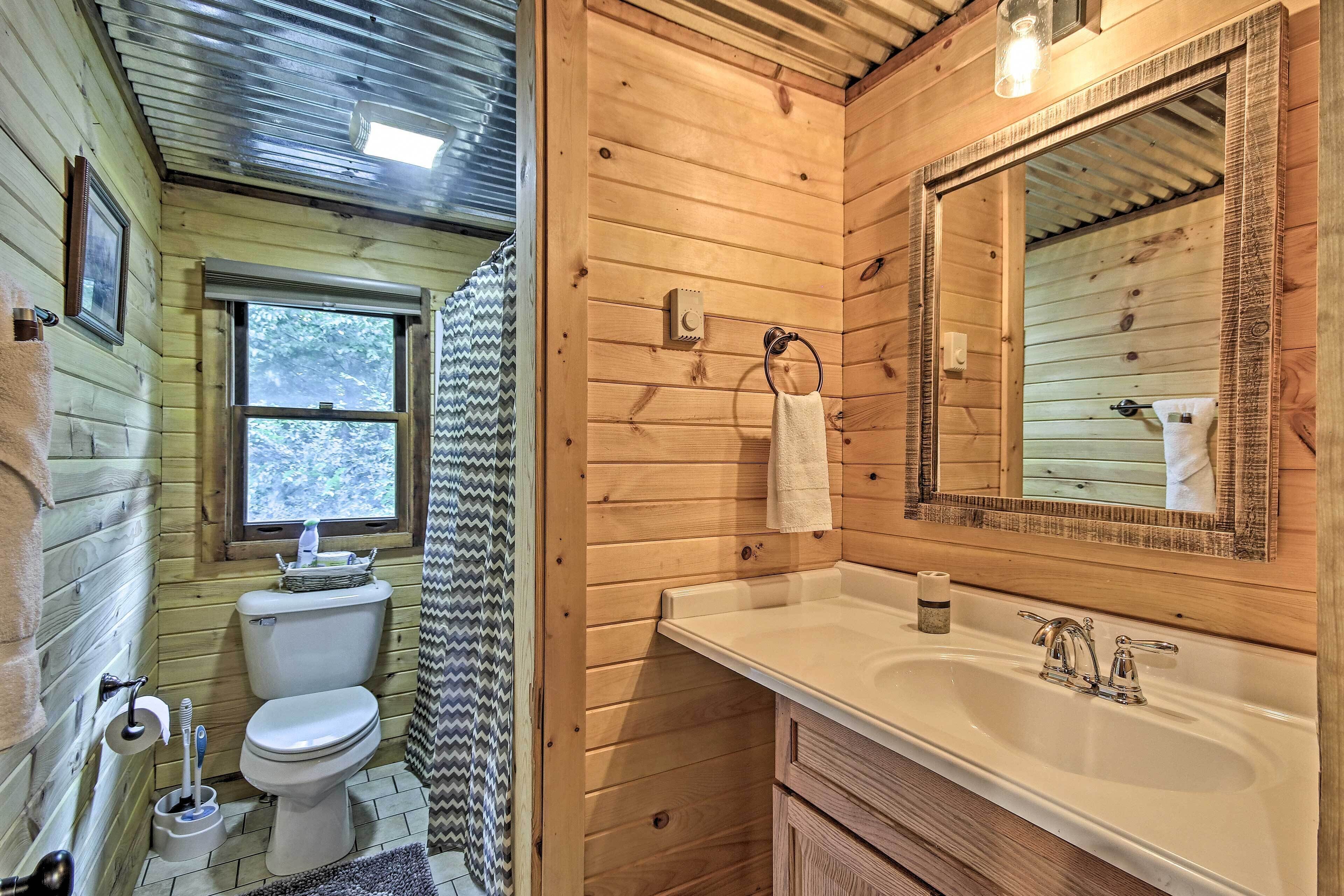 Une salle de bain rustique, aménagée dans une cabane en bois, avec des toilettes, un lavabo et un miroir.