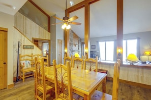 A dining area with a wooden table and chairs, a ceiling fan, and a staircase leading to another level.