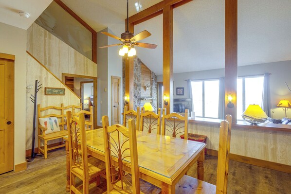 A dining area with a wooden table and chairs, a ceiling fan, and a staircase leading to another level. - Mountainside Home: Stunning Views in Granby Ranch! (Granby)