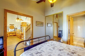 A bedroom with a bed, a wooden door, a mirror, and a staircase leading to a dining area. - Mountainside Home: Stunning Views in Granby Ranch! (Granby)