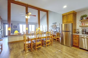 A spacious kitchen with wooden cabinets, a stainless steel refrigerator, and a dining area with wooden chairs and a glass table.