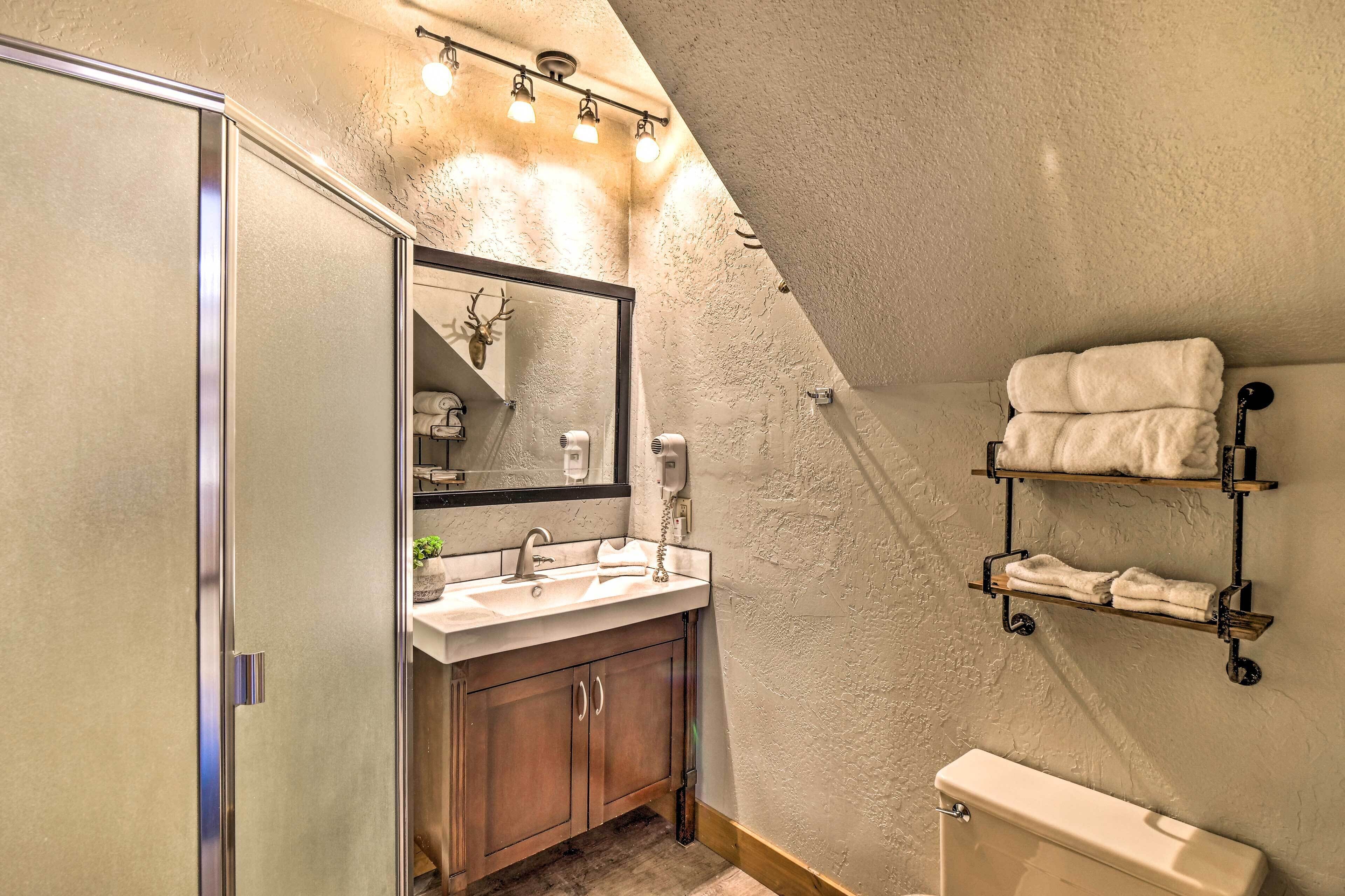 Un baño con lavamanos, espejo, toallero y retrete.