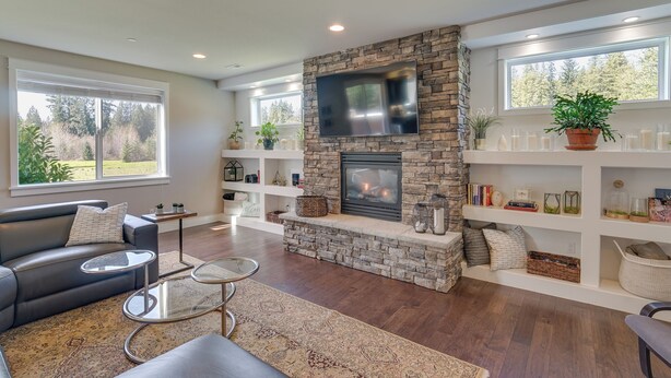 A modern living room with a stone fireplace, large windows, and a comfortable seating area. - Spacious Carnation Home w/ Grill & Large Yard (Carnation)