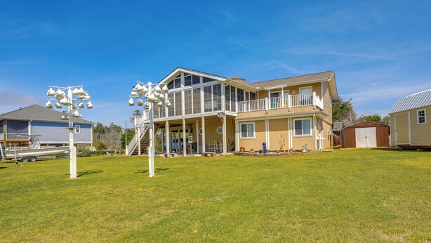Une maison à deux étages avec une grande véranda à l’avant, une terrasse couverte et un garage.