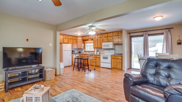 A modern living room with a leather sofa, a TV, and a kitchen in the background. - Shell Knob Home w/ Fire Pit, Near Table Rock Lake! (Shell Knob)