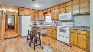 A kitchen with wooden cabinets, a white refrigerator, a microwave, and a stove. - Shell Knob Home w/ Fire Pit, Near Table Rock Lake! (Shell Knob)