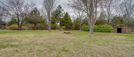 A grassy field with trees and a wooden structure.