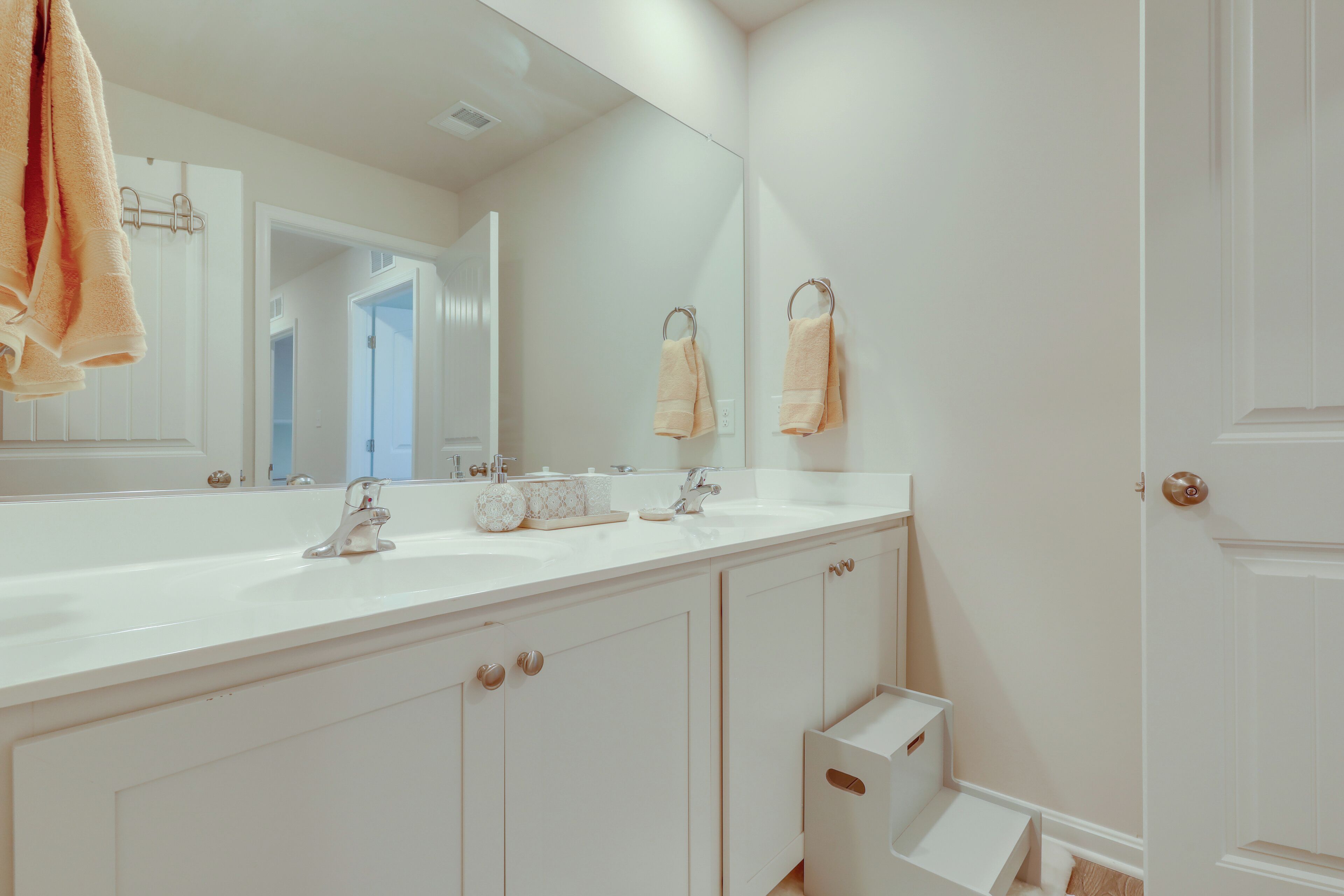 Une salle de bain avec un lavabo blanc, deux porte-serviettes et un grand miroir.