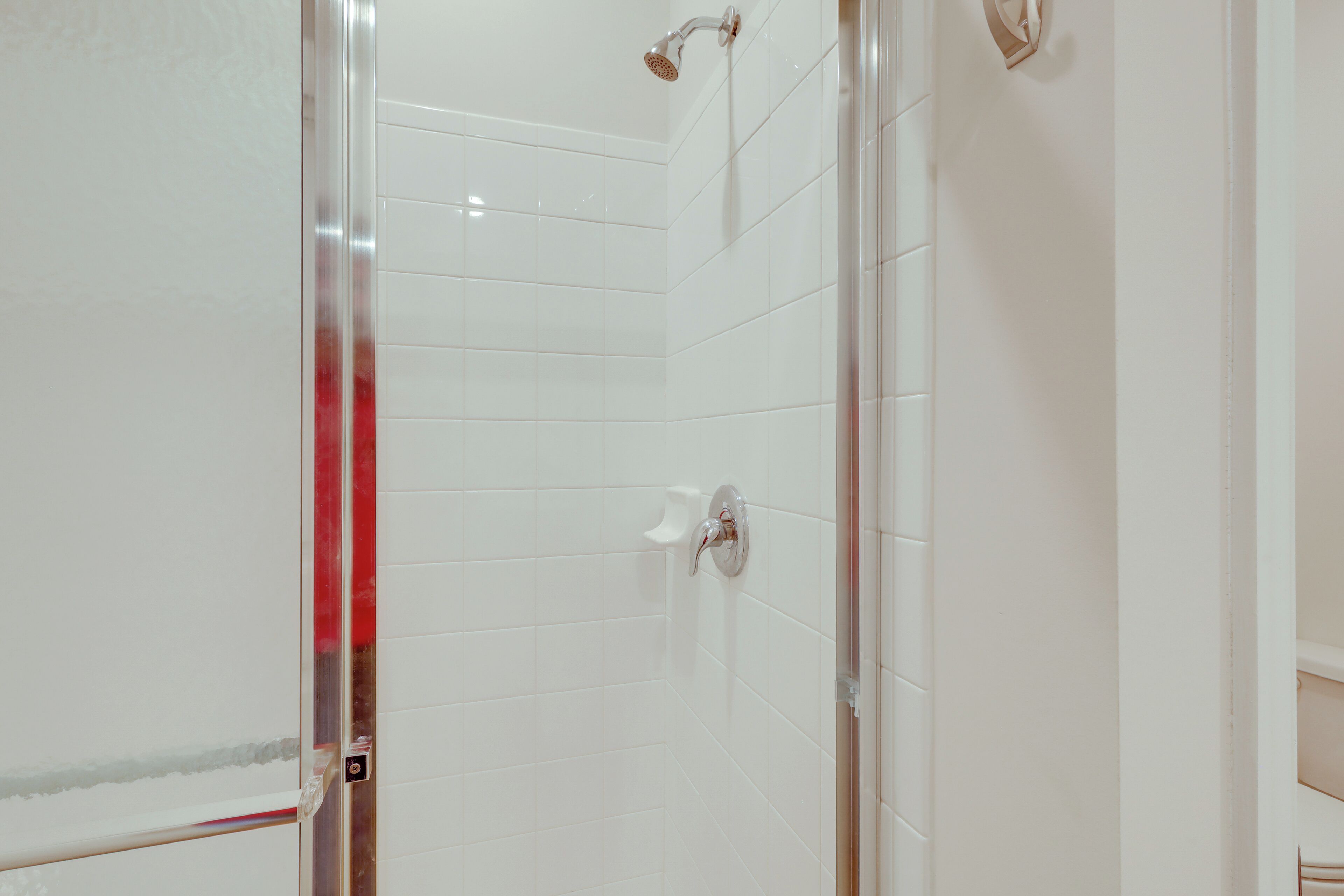 Eine Dusche mit weißen Fliesen und einer Glastür.