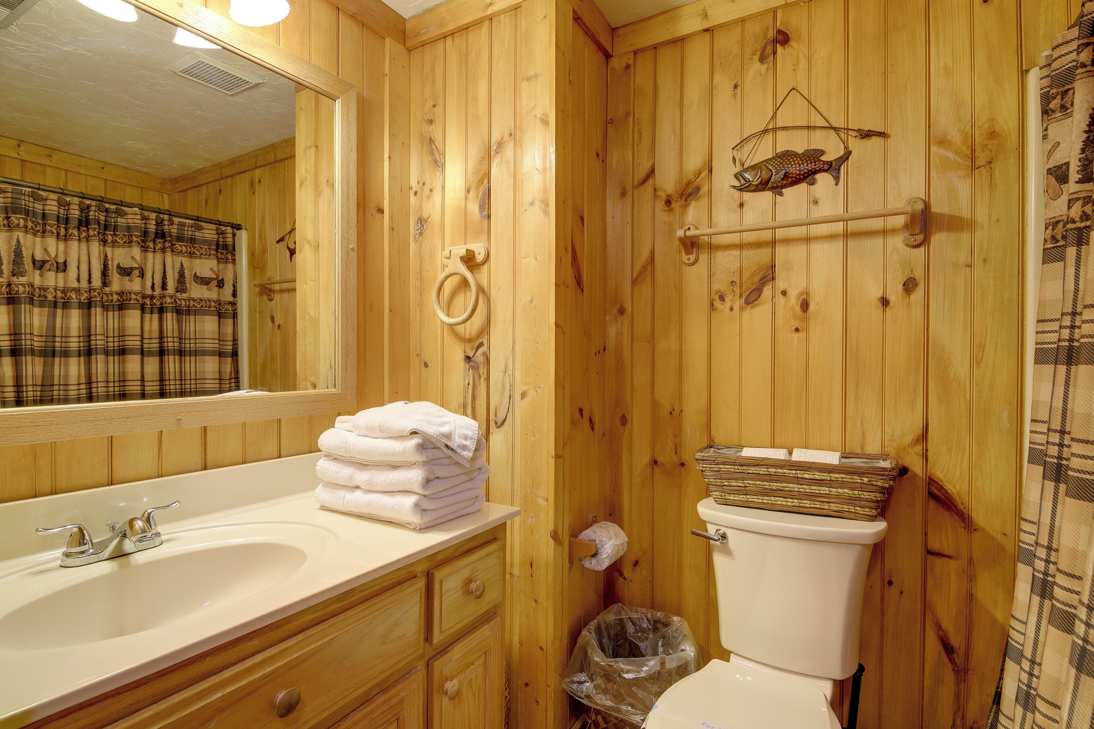 A wooden bathroom with a sink, toilet, and a mirror.