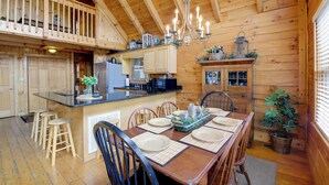 A wooden cabin interior with a dining area, kitchen, and a balcony. - Smoky Mountains Cabin w/ Hot Tub, Deck & Views! (Sevierville)