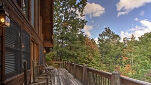 A wooden deck with chairs and a railing overlooking a forested area. - Smoky Mountains Cabin w/ Hot Tub, Deck & Views! (Sevierville)