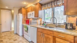 A kitchen with wooden cabinets, a microwave, a coffee maker, a toaster, and a sink. - Ski Condo w/ Pool, Close to Story Land & Attitash! (Glen)
