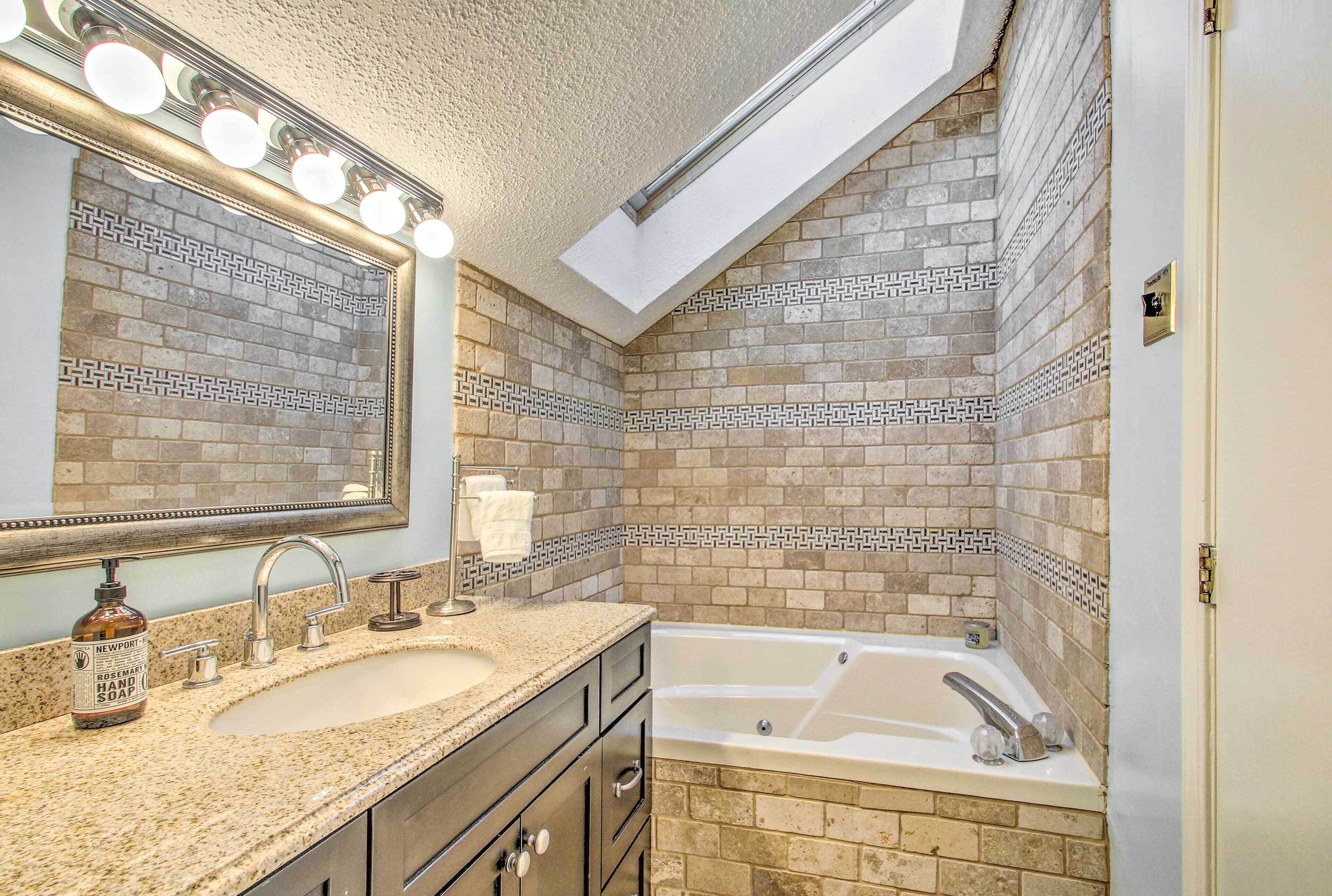 Une salle de bain avec un grand miroir, un lavabo, une baignoire et un meuble-lavabo avec des tiroirs.