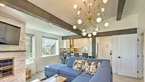 A modern living room with a sectional sofa, a fireplace, and a dining area in the background. - Snowmass Condo: Great Proximity to Chair Lift (Snowmass Village)