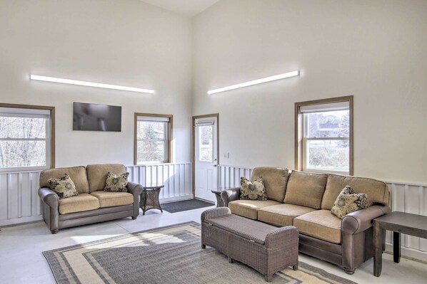 A spacious living room with two sofas, a coffee table, and a rug. - Spacious Recently Built Home < 1 Mi to Lake! (Malone)