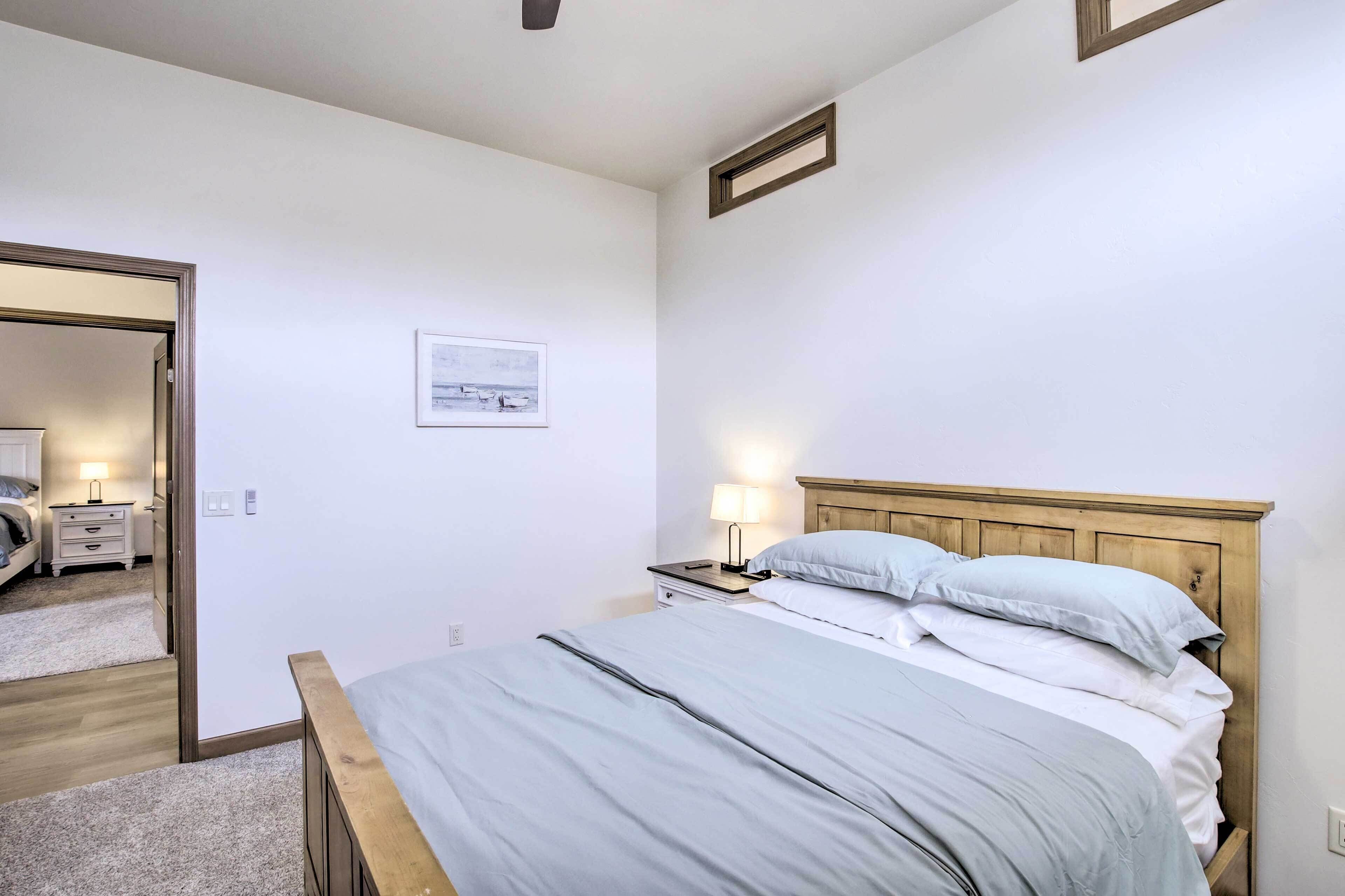 Um quarto com cama, mesa de cabeceira, luminária e um quadro na parede.