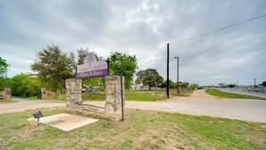 A stone sign with the text "Invwood Estates Winery & Bistro" in a rural setting with a dirt road and greenery. - Studio in Fredericksburg Winery w/ Shared Hot Tub (Fredericksburg)
