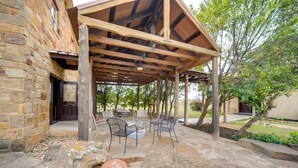 An outdoor patio with stone flooring, rustic wooden beams, and metal chairs. - Studio in Fredericksburg Winery w/ Shared Hot Tub (Fredericksburg)
