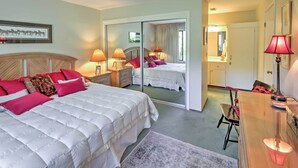 Une chambre d’hôtel avec un grand lit, deux tables de chevet avec des lampes, une chaise, un bureau et un miroir.